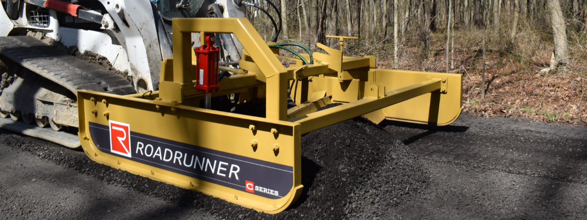 skid steer grader in action in forest setting with leaves on the ground