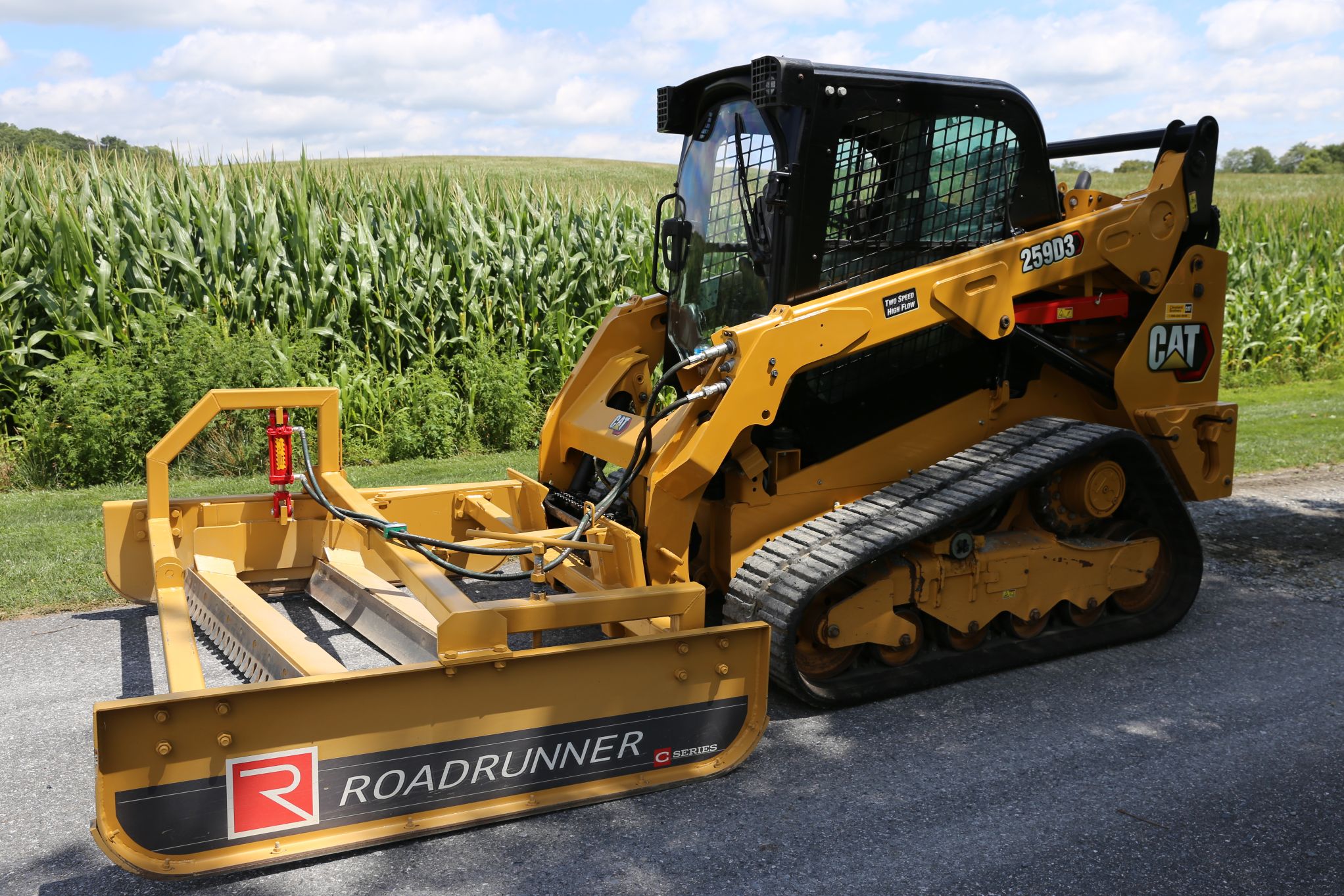 Compact tractor with Roadrunner grader blade smoothing a gravel road, showcasing dual blades, rugged steel frame, and precise grading action