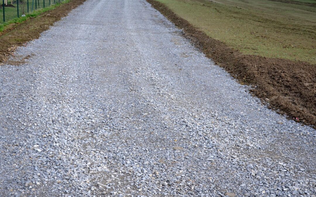 A freshly repaired gravel road that is level, with culvert ditches dug on either side