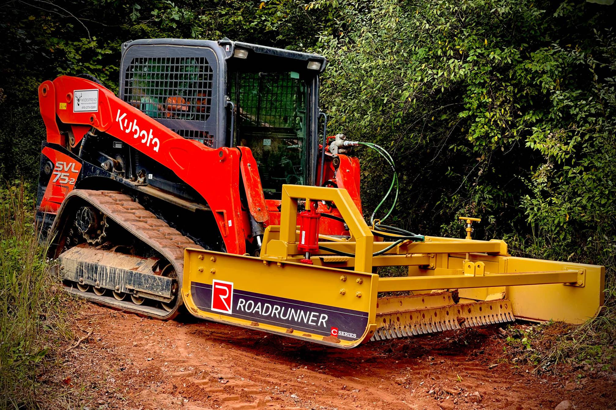 Compact tractor with Roadrunner grader blade smoothing a gravel road, showcasing dual blades, rugged steel frame, and precise grading action